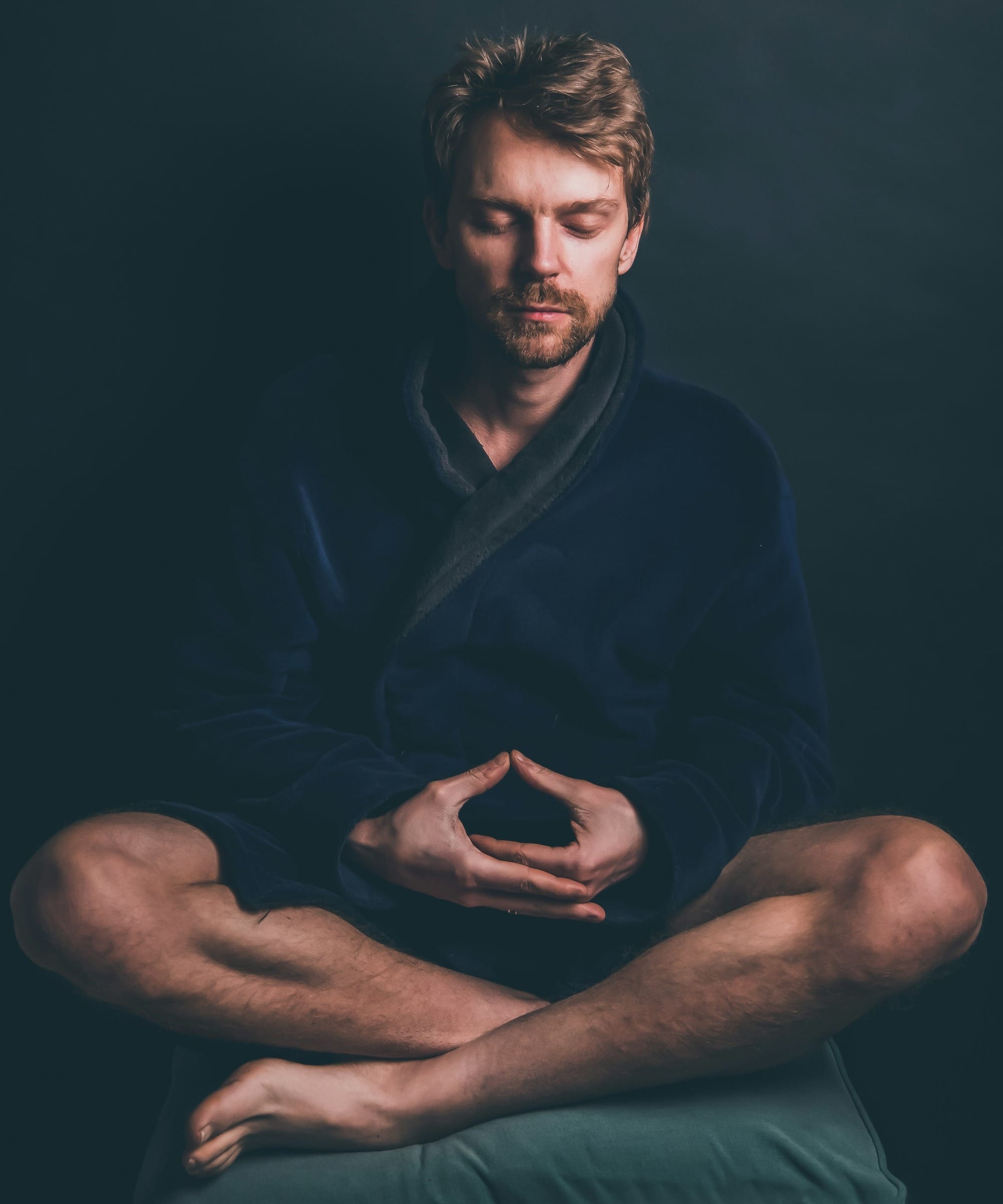 man in black hoodie sitting on black background