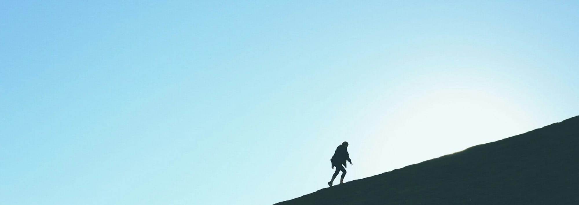 silhouette of man climbing hill